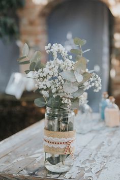 a mason jar filled with baby's breath flowers on top of a wooden table