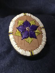 a purple flower is sitting on top of a piece of brown cardboard with white and yellow strips