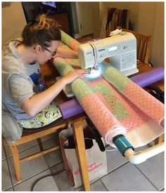 a woman sitting at a table using a sewing machine