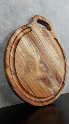 a wooden cutting board sitting on top of a black table next to a gray wall