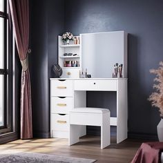 a white dressing table with drawers and stool in a room next to a window,