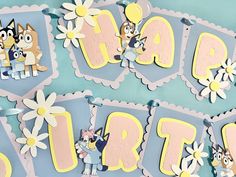 a birthday banner with cartoon animals and flowers on it's sides, hanging from the wall