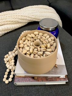 a bowl filled with nuts sitting on top of a table next to a book and white blanket