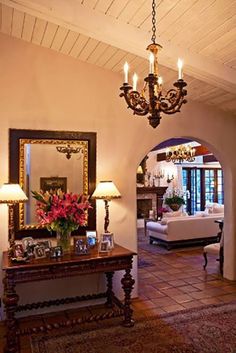 a living room filled with furniture and a chandelier hanging from the ceiling next to a doorway