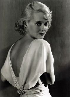 a black and white photo of a woman in a dress with her back to the camera