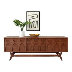 a wooden sideboard with a plant on top and a vase in front of it