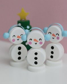 three snowmen are standing next to a small christmas tree with a star on top