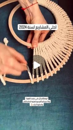 two hands are working on a piece of art that is being made out of rope