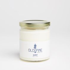 an old pine candle is sitting on a white surface with a gold lid and label