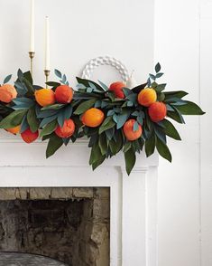 an arrangement of oranges and greenery on a mantel above a fire place