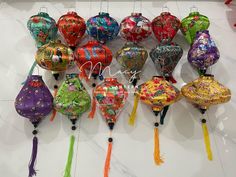 there are many colorful lanterns hanging on the wall with tassels attached to them