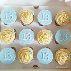 twelve cupcakes with blue frosting and white numbers on the top are arranged in a box