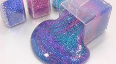 purple and blue glittered soaps in plastic containers on a white surface with one container open