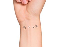 a woman's wrist tattoo with birds on it