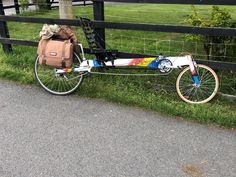 a bike parked next to a fence with a bag on the front wheel and back tire