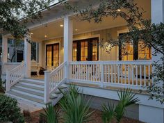 a white house with porches and stairs leading to the front door at night time