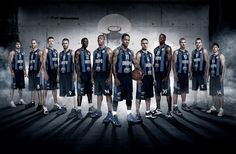 a group of basketball players standing next to each other in front of a dark background