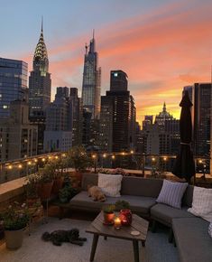 a couch and table on a roof with city lights in the background