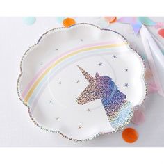 a paper plate with a unicorn face on it and confetti scattered around it