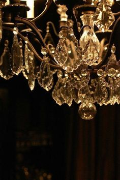 a chandelier hanging from the ceiling in a dark room with candles on it