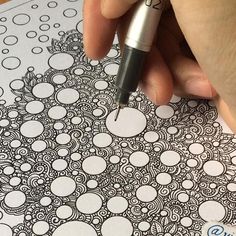 a person is holding a pen and drawing something on a coloring page with bubbles in the background