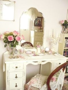 a white desk with pink flowers on it and a chair in front of the mirror