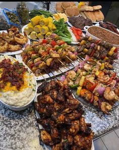 many different types of food are on display at a buffet table, including skewered meats and veggies