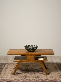 a wooden table sitting on top of a rug next to a bowl filled with plants