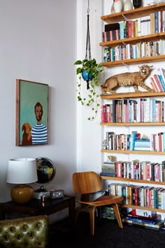 a living room filled with lots of books and furniture next to a wall mounted book shelf