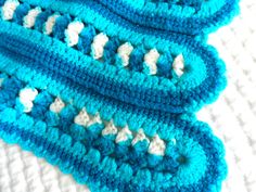 a crocheted blue and white dishcloth laying on top of a table cloth