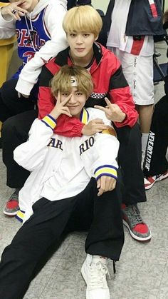 two boys are sitting on the floor with their arms around each other and one boy is covering his face