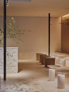 an empty room with tables and stools next to a tree in the corner,