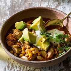 a bowl filled with beans and avocado on top of a wooden table