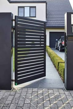 an open gate leading to a house with a car parked in the driveway behind it