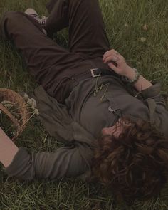 a person laying in the grass with their head on his hand and holding a cell phone