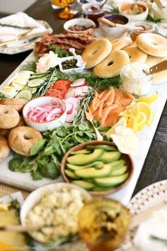 an assortment of food is laid out on a long serving platter with breads and bagels