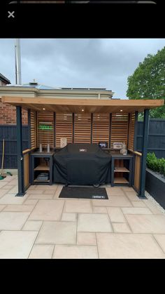 an outdoor bbq grill in the middle of a patio with a cover over it