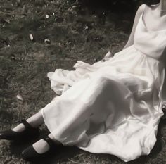 black and white photograph of a woman in a dress laying on the ground with her legs crossed