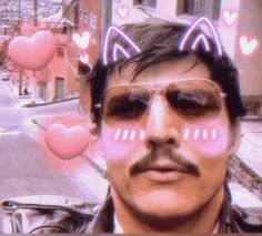 a man with cat ears on his head and pink hearts floating above him in the air