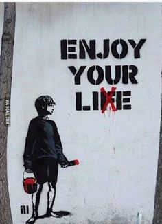 a painting on the side of a building that says enjoy your life with a boy holding a bucket