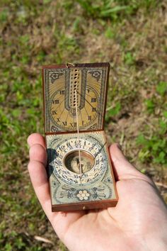 a hand holding an old fashioned compass in it's case