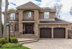 a large brick house with two garages and steps leading up to the front door