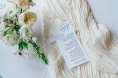 a bouquet of flowers sitting next to a piece of paper on top of a table