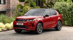 a red range rover parked in front of a house