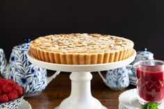 there is a pie on the table with raspberries and other dishes around it