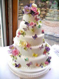 a three tiered wedding cake decorated with flowers and butterflies