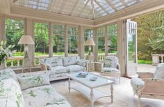 a living room filled with white furniture and lots of glass doors leading to an outside patio