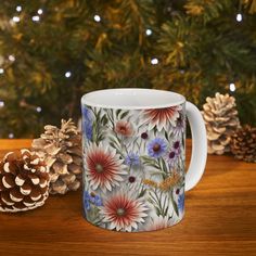 a coffee mug sitting on top of a wooden table next to a pine cone and christmas tree