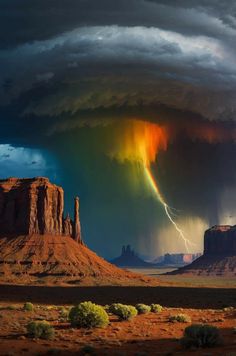 a rainbow appears in the sky over a desert landscape with mountains and rocks under a cloudy sky