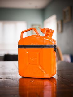 an orange gas can sitting on top of a wooden table